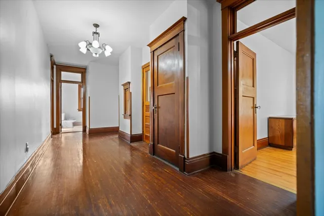 a view of a hallway with wooden floor and chandelier