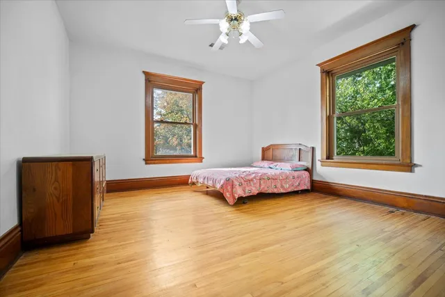 a bedroom with a bed and a dresser with wooden floor