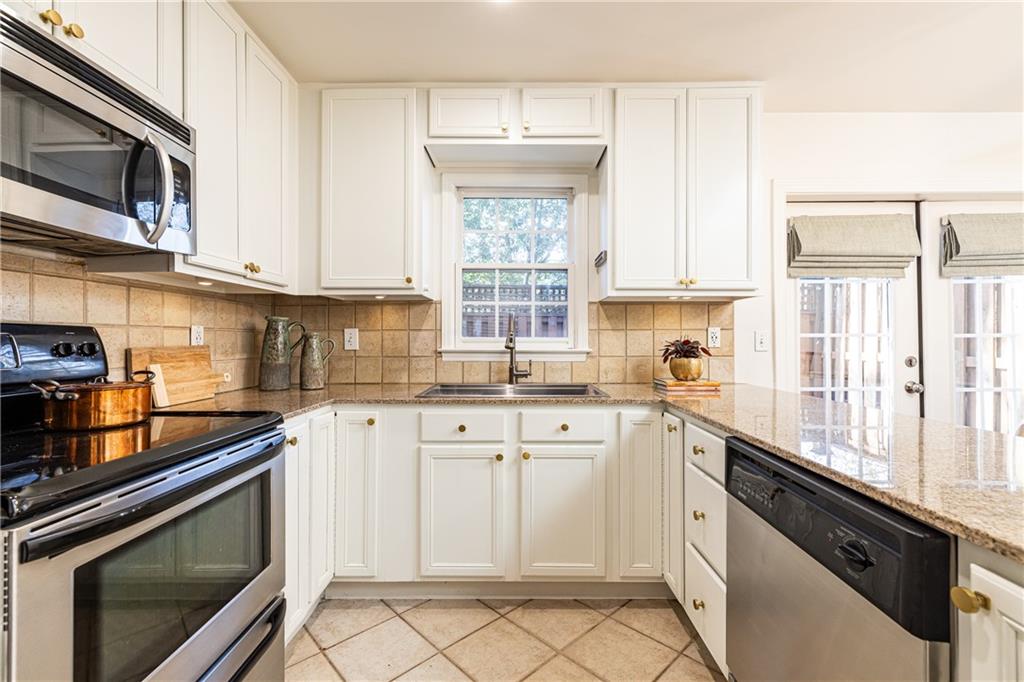 1101 Collier Road Northwest, Unit I3 Atlanta, GA 30318 - Photo 12 of 24 a kitchen with granite countertop white cabinets white appliances a sink and a window