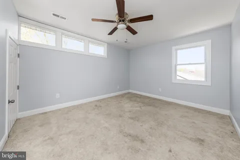 an empty room with windows and fan