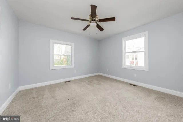 an empty room with a window and a fan