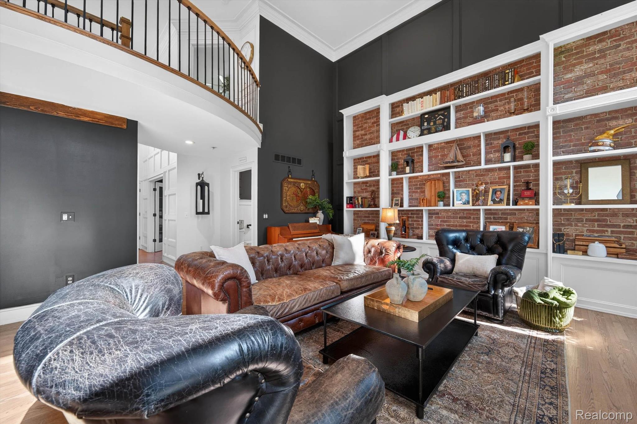 371 Lone Pine Circle Rochester, MI 48307 - Photo 12 of 59 Open-concept living area featuring double-height ceilings, a second-story interior balcony with black wrought iron railing, and wood-finish flooring