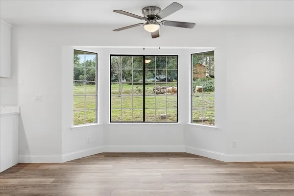 a view of an empty room with a window and a ceiling fan