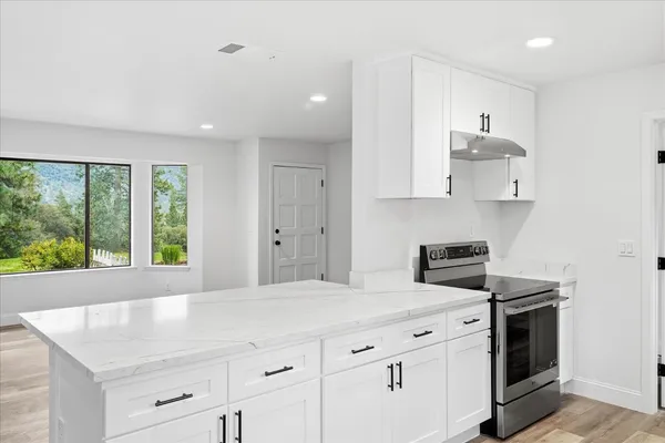 a kitchen with stainless steel appliances granite countertop a stove a sink and white cabinets