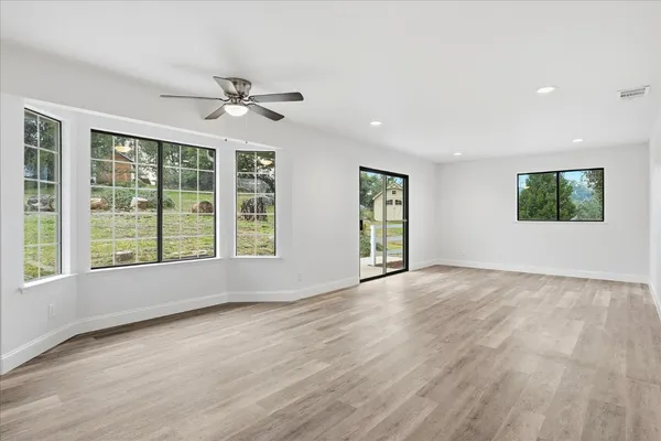 a view of an empty room with a window and wooden floor