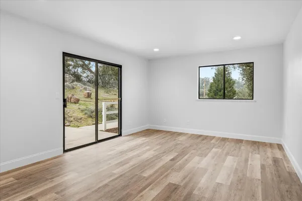 an empty room with wooden floor and windows