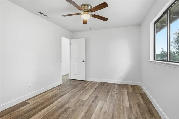 an empty room with a window and a ceiling fan