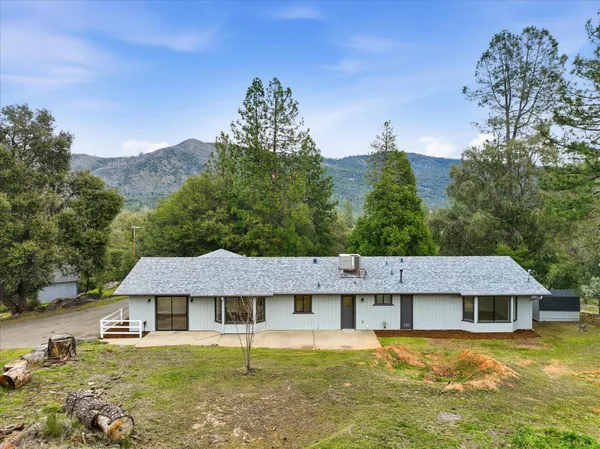 a front view of a house with a garden and a tree