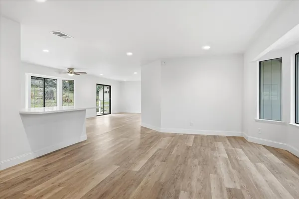 an empty room with wooden floor and windows