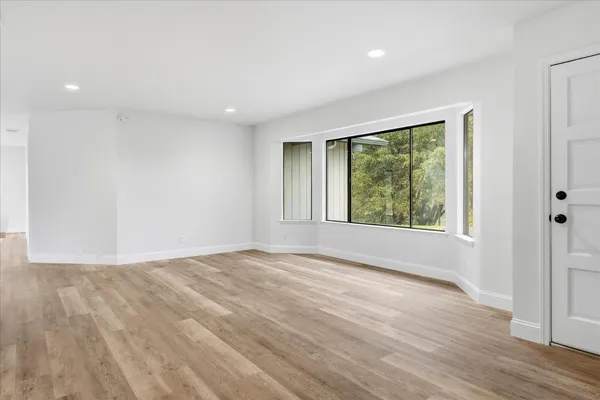 a view of an empty room with wooden floor and a window