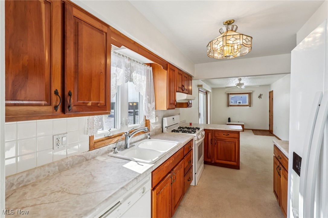 970 Eastern Road Doylestown, OH 44230 - Photo 12 of 49 Kitchen with white appliances, brown cabinets, light countertops, light colored carpet, and a peninsula