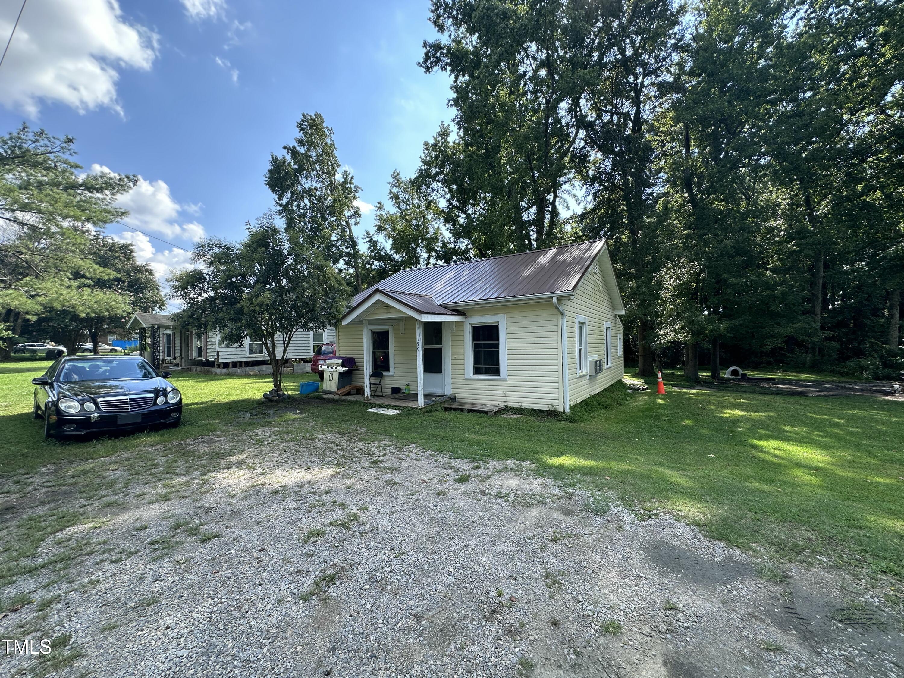 129 Spring Valley Road Henderson, NC 27536 - Photo 4 of 14 a front view of a house with a garden and trees