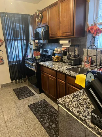 a kitchen with stainless steel appliances granite countertop a stove a sink and a microwave