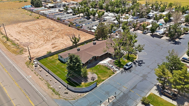 416 Kari Parowan, UT 84761 - Photo 12 of 14 Expansive corner lot featuring a ranch-style residence with a brown shingle roof, established landscaping, a curved retaining wall, and a large adjacent cleared parcel
