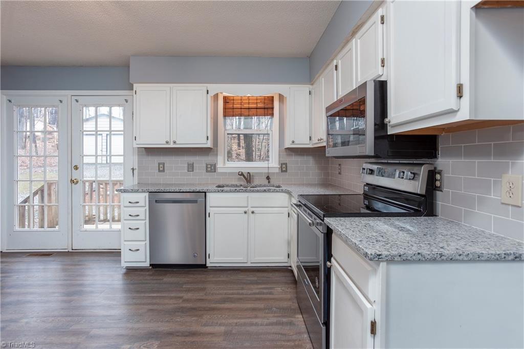 7325 Goodwill Church Road Oak Ridge, NC 27310 - Photo 7 of 20 WOW, beautiful kitchen with granite counters, tile backsplash, BRAND NEW stainless steel appliances, double sink, and pantry to the left