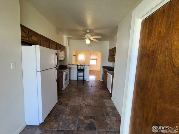 a view of a refrigerator in kitchen and an empty room