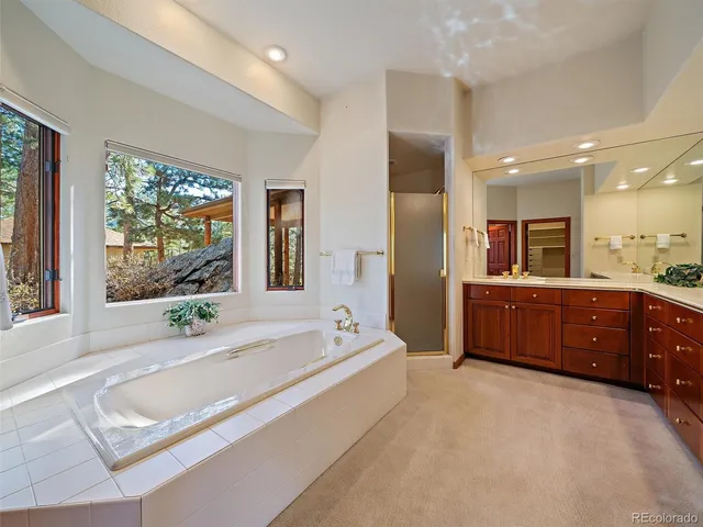 a spacious bathroom with a tub sink and mirror