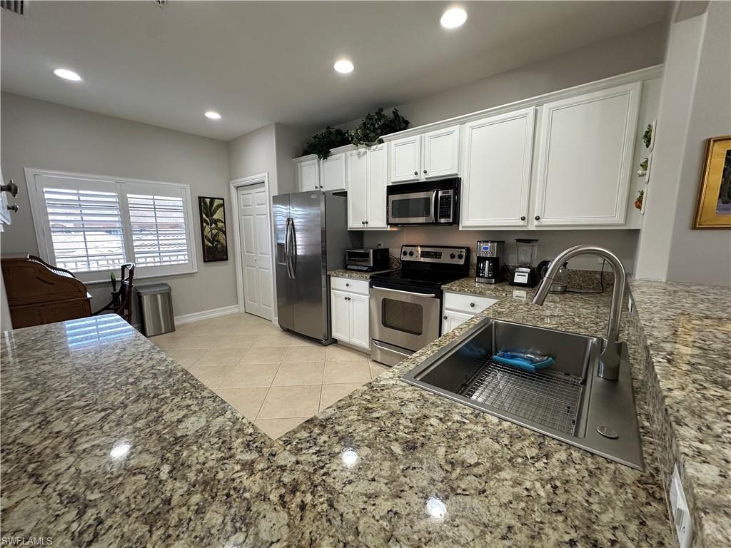 9113 Michael Circle, Unit 7710 Naples, FL 34113 - Photo 5 of 34 a kitchen with stainless steel appliances granite countertop a sink stove microwave and refrigerator