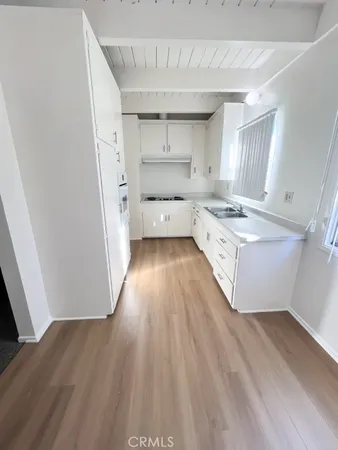 a kitchen with a wooden floor and white stainless steel appliances