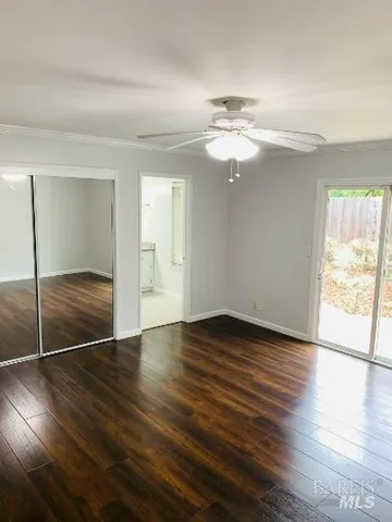 an empty room with wooden floor fan and windows