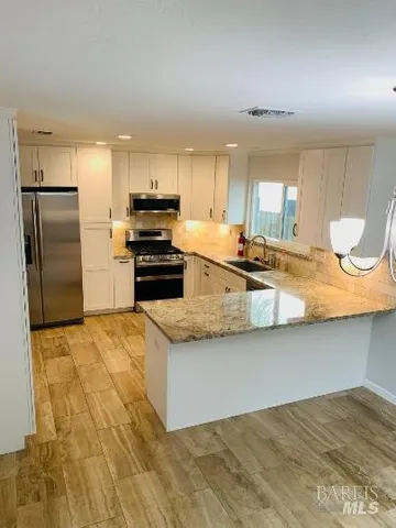 a kitchen with stainless steel appliances granite countertop a sink a stove counter space and cabinets