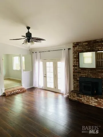 a view of an empty room with wooden floor fireplace and a window