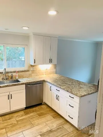 a kitchen with granite countertop white cabinets and a sink