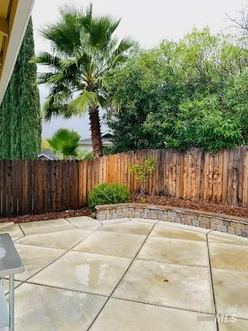 a backyard of a house with plants and trees with wooden fence