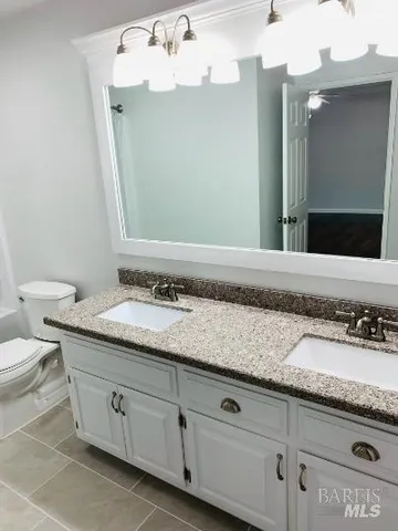 a bathroom with a granite countertop sink a toilet and mirror
