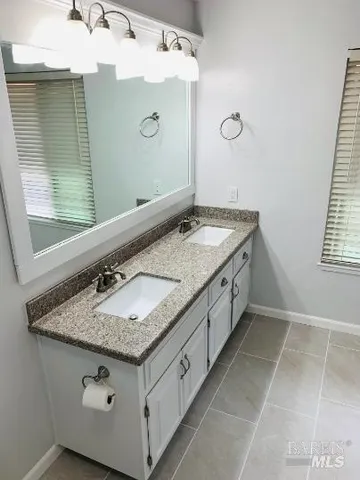 a bathroom with a granite countertop sink and a mirror