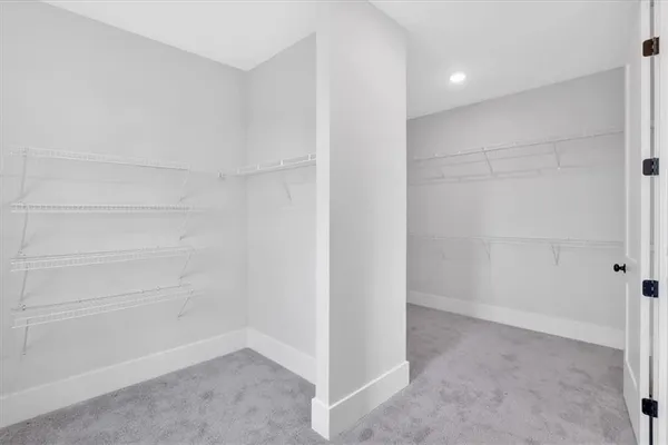 a view of a hallway with wooden floor and a bathroom