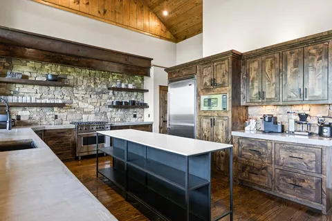 a large kitchen with stainless steel appliances kitchen island granite countertop a table chairs in it and wooden floor