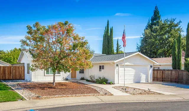 a front view of a house with a yard and tree