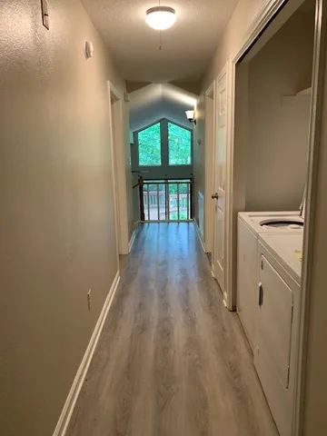 a view of a hallway with wooden floor and a living room