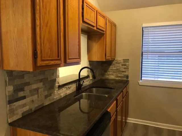 a kitchen with granite countertop a sink a stove and cabinets