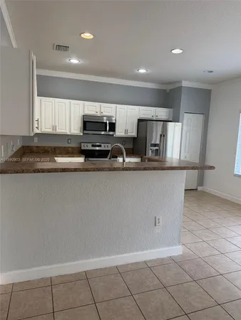 a kitchen with stainless steel appliances a sink a stove a microwave a sink a refrigerator and cabinets