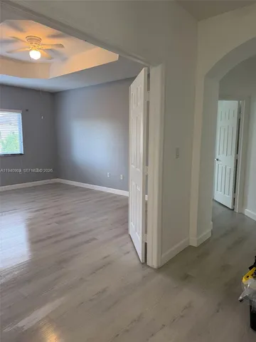 a view of an empty room with wooden floor and a window