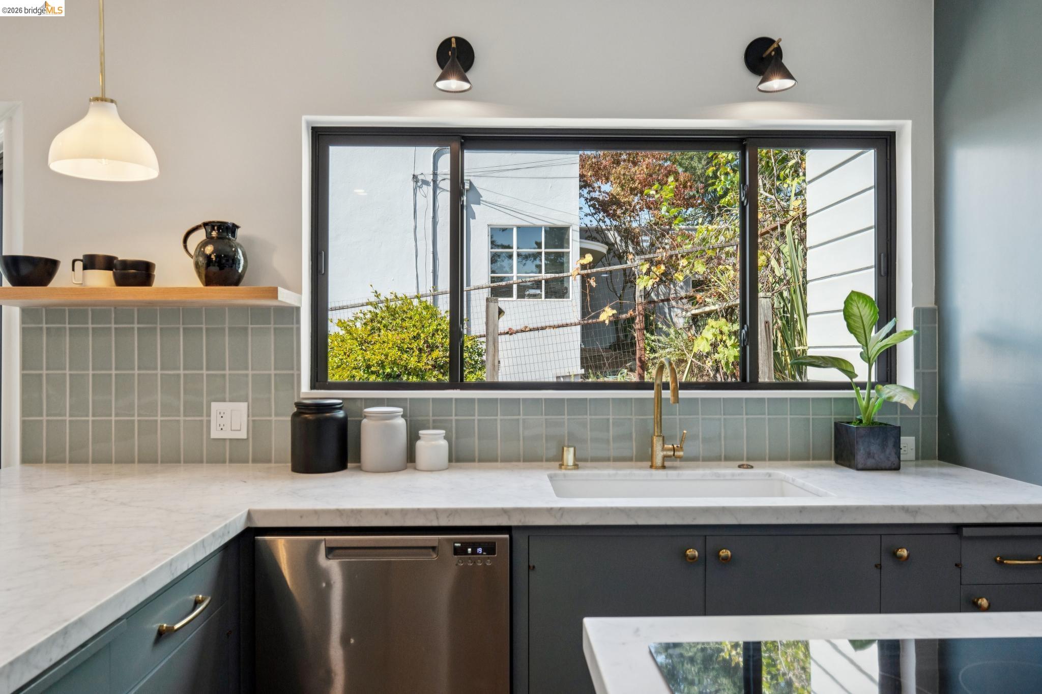 38 Highgate Road Kensington, CA 94707 - Photo 14 of 78 Integrated stainless steel dishwasher, white stone countertops, deep blue cabinetry with brass hardware, and a single basin sink with a brass-finish faucet