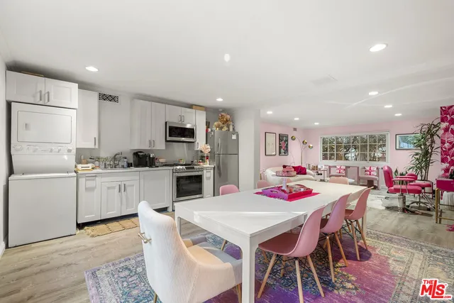 a kitchen with a dining table cabinets appliances and wooden floor