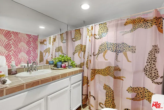 a bathroom with a sink and mirror with shower