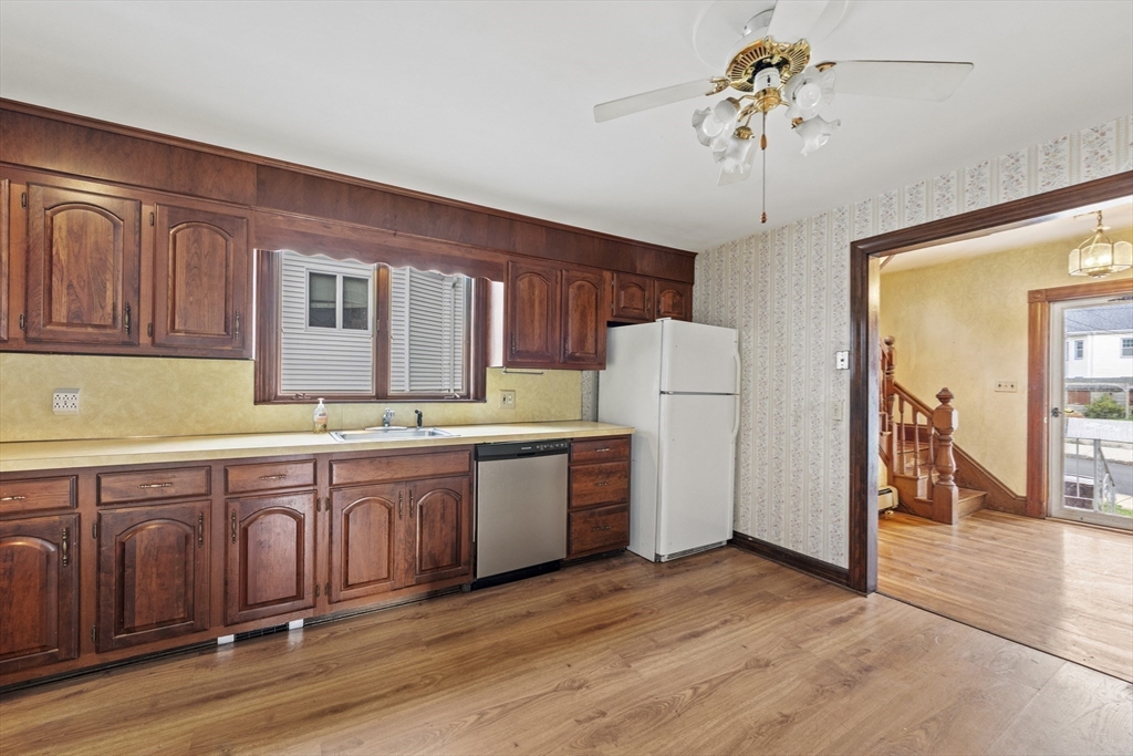 12 Foster Street Everett, MA 02149 - Photo 12 of 29 a large kitchen with stainless steel appliances granite countertop a refrigerator a sink dishwasher a stove and white cabinets with wooden floor