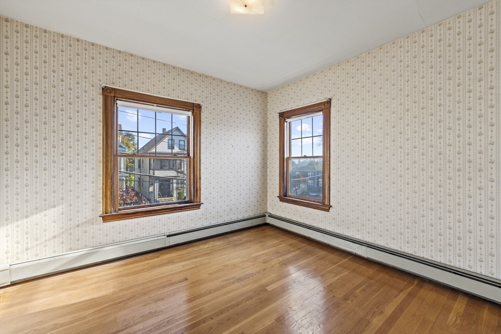 12 Foster Street Everett, MA 02149 - Photo 23 of 29 an empty room with wooden floor and windows