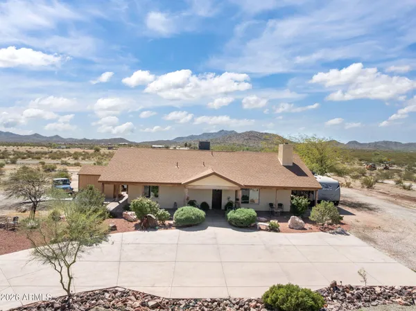 a front view of a house with a yard and mountain view in back