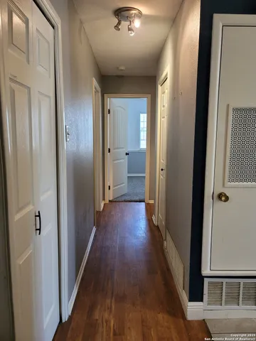 a view of a hallway with wooden floor and a bathroom