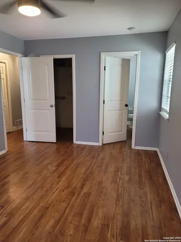 a view of an empty room with wooden floor & closet