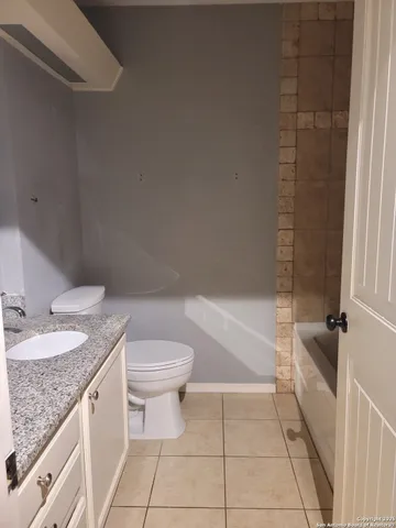a bathroom with a granite countertop sink a toilet and bathtub