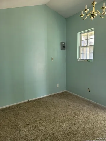 an empty room with a chandelier fan and windows