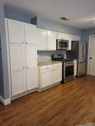 a kitchen with cabinets stainless steel appliances and wooden floor