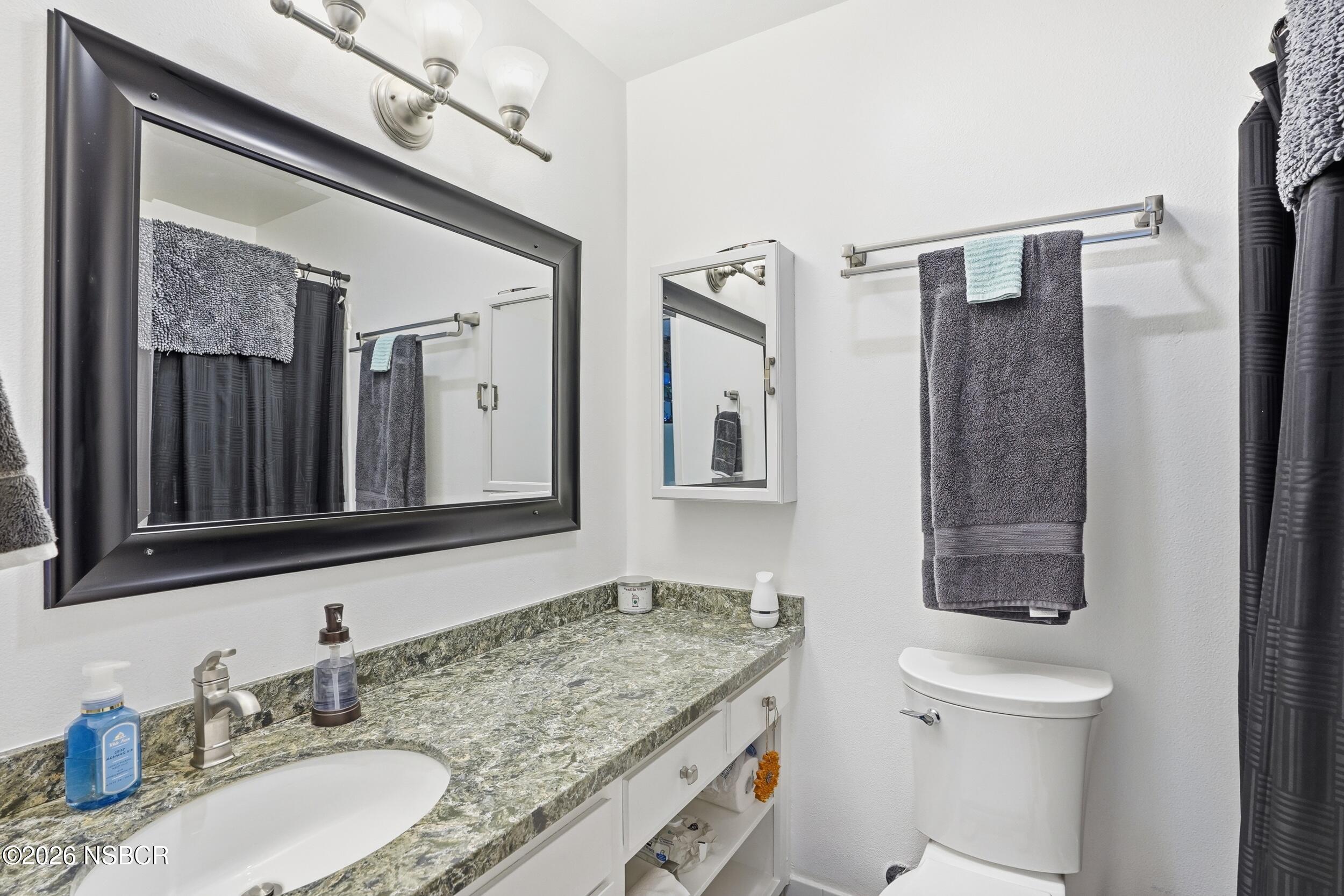 218 North R Street Lompoc, CA 93436 - Photo 20 of 24 a bathroom with a granite countertop sink toilet and shower