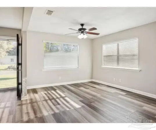 a view of an empty room with a window and wooden floor